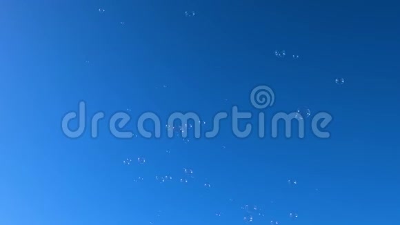 透明气泡在晴朗的蓝天背景上飞行气泡漂浮运动4k视频的预览图