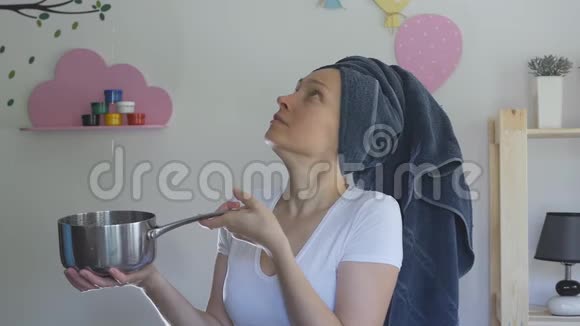 一个女人头上有一条毛巾用一个金属平底锅从天花板上接住水滴视频的预览图