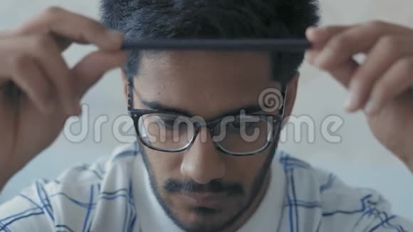 特写镜头戴眼镜的印度学生在铅笔手中旋转在自己面前摆出一副咄咄逼人的样子准备考试视频的预览图