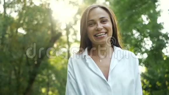 在秋天公园里特写一幅微笑而快乐的女性女孩的肖像迷人的小姐在挥手视频的预览图