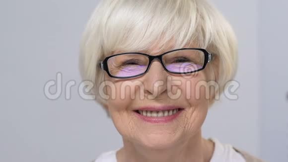 戴眼镜的老年妇女微笑着闭上一只眼睛在诊所检查视力视频的预览图