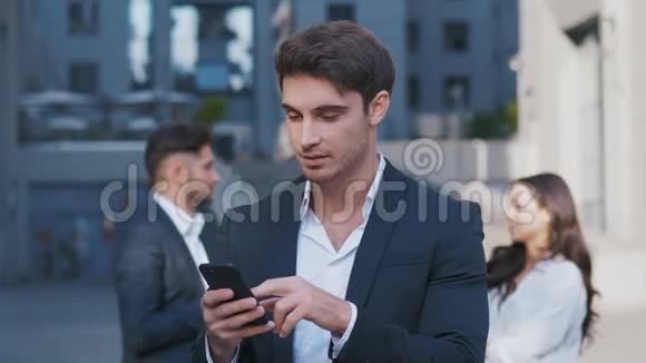 英俊的商人在他的智能手机上使用应用程序在商业区的街道上查新闻梅尔斯看上去视频的预览图