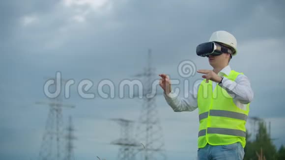 中期计划男性能源工程师在虚拟现实眼镜和白色头盔背景下的高压电力视频的预览图