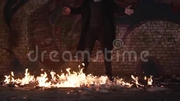 一个穿着黑色衣服的人站在一座废弃建筑的燃烧的地板上张开双臂拍摄一个剪辑慢动作视频的预览图