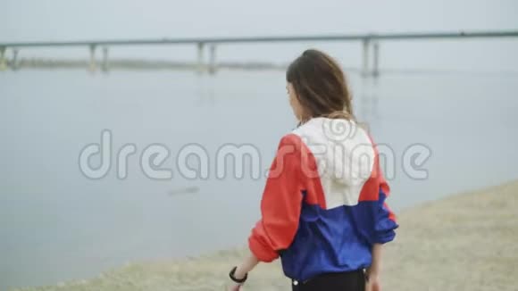 美丽的年轻女子走在河边年轻女子沿着水走视频的预览图