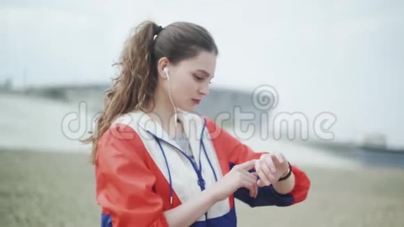 年轻女子跑步并检查她的运动手表上的心脏训练数据视频的预览图