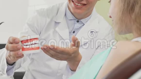 持牙模的男牙医向病人解释牙齿护理视频的预览图