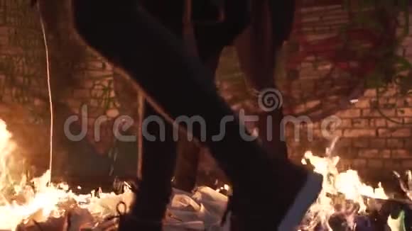两个穿黑衣的人倒出一种易燃液体在一座废弃的建筑里燃烧着火拍摄一个剪辑慢慢视频的预览图