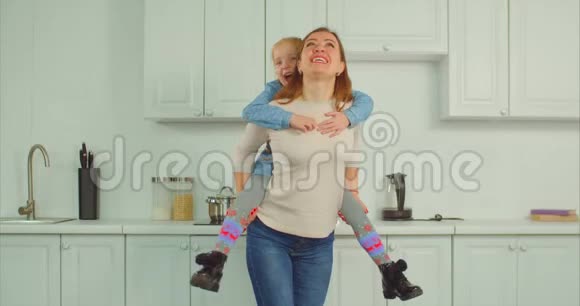 无忧无虑的母亲在厨房里驮着兴奋的孩子视频的预览图