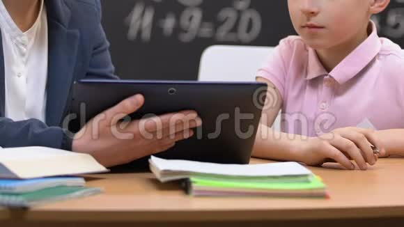 女老师拿着平板电脑向小男孩解释信息视频的预览图