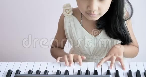 穿着白色连衣裙的女孩正在弹钢琴视频的预览图