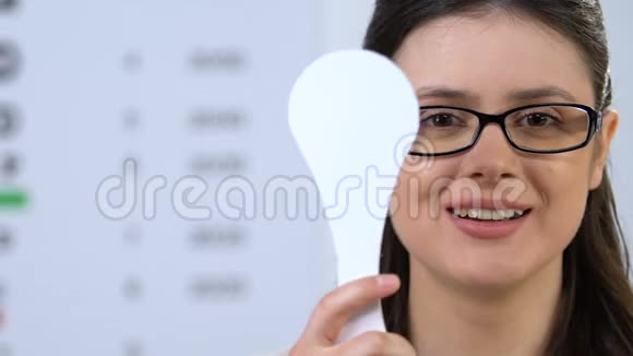 戴眼镜的快乐女人闭上一只眼睛视力检查装置医疗保健视频的预览图
