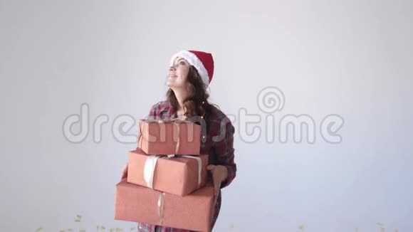 年轻快乐的女人戴着圣诞帽手里拿着白色背景的礼品盒跳舞假期概念视频的预览图
