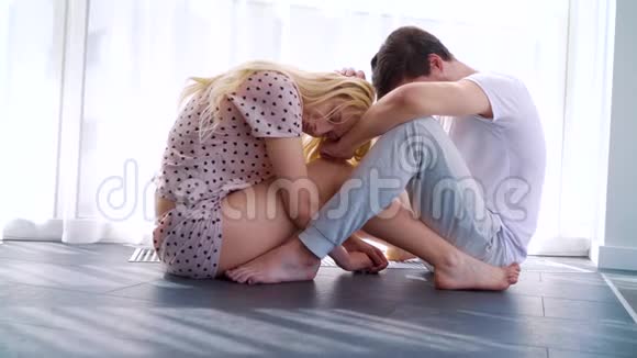一对年轻夫妇坐在地板上低着头沮丧的早晨视频的预览图