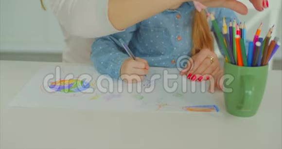 妈妈和孩子的手在书桌上创作艺术品视频的预览图