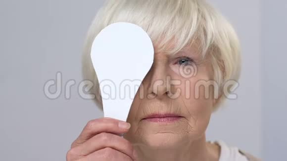 微笑老年女性斜视视力检查闭上一只眼睛健康视频的预览图