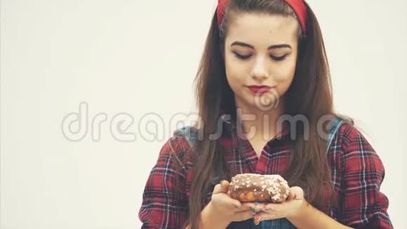 可爱的年轻女性建议你品尝大巧克力甜甜圈通过她的脸表情显示它是非常美味的视频的预览图