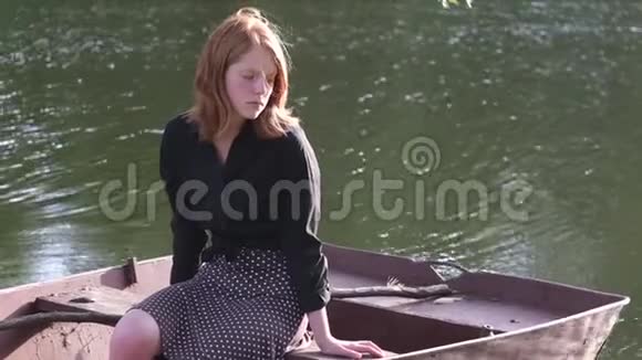 美丽的姜姑娘坐在船上悲伤视频的预览图