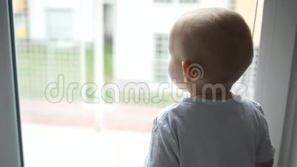 一个穿着白色T恤的两岁小男孩独自在窗外沉思着说了些什么单身子女视频的预览图