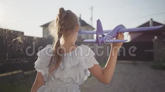 可爱的小女孩站在院子里手里拿着一架玩具飞机准备发射玩具飞机的孩子视频的预览图