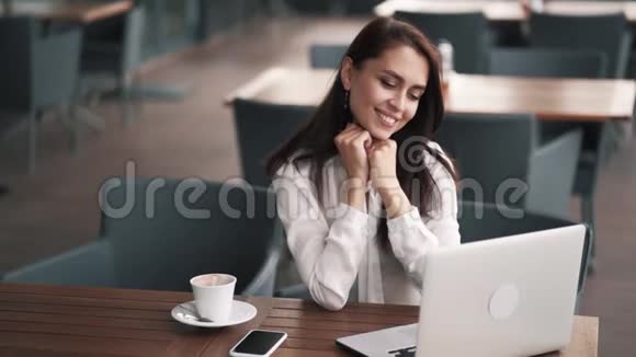 女商人坐在咖啡馆里微笑着看着笔记本电脑屏幕慢动作视频的预览图