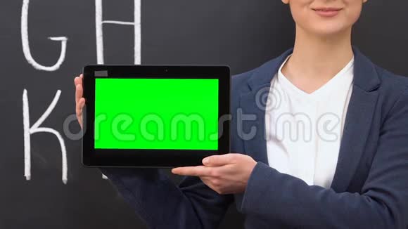女教师手持绿色屏幕平板电脑在线课程教育视频的预览图