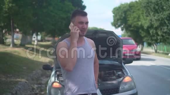 在一条乡村道路上的汽车抛锚后一个心烦意乱的人打电话来提供汽车服务焦急的男人在电话里说话视频的预览图