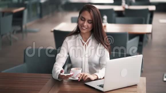 漂亮的女商人在咖啡馆里打电话桌上有笔记本电脑慢动作视频的预览图