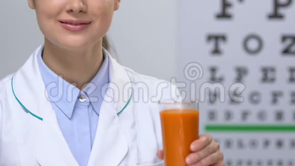 微笑女医生用眼图背景显示胡萝卜汁健康视频的预览图