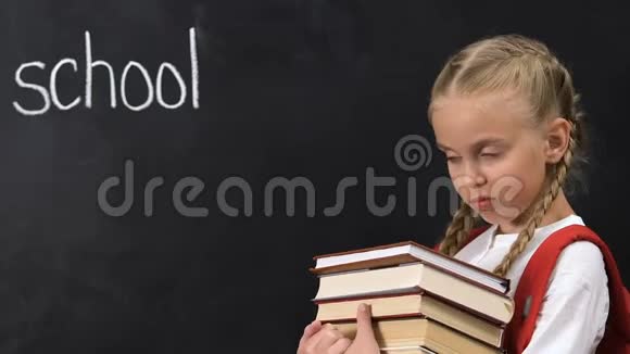 顽皮的女孩拿着没有手势的书黑板上写着学校的单词视频的预览图