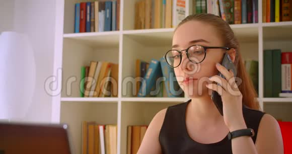 年轻成功的红头发女商人戴眼镜手提电脑在办公室打电话视频的预览图