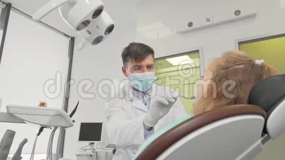 男牙医在他的诊所检查一个小女孩的牙齿视频的预览图