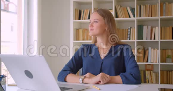 年轻迷人的白种人女商人的特写镜头她兴高采烈地坐在办公桌前看着镜头视频的预览图