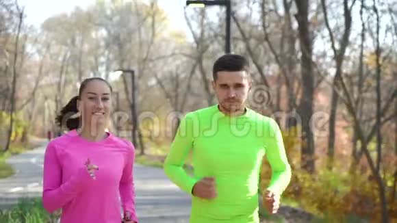 阳光明媚的秋天公园里快乐的运动情侣慢跑视频的预览图
