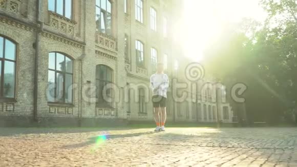 英俊的年轻人站在大学大楼前看着摄像机年轻人庆祝她的毕业典礼太阳视频的预览图