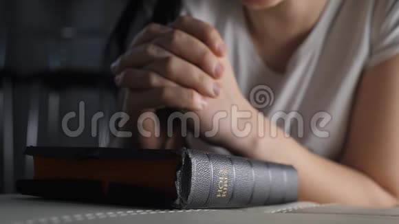 女孩在睡前用圣经在室内祈祷宗教观念晚祷妇女深色手圣经生活方式视频的预览图