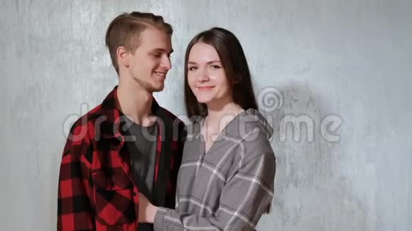 年轻漂亮的夫妇男人和女人温柔地拥抱在房子的灰色墙壁上视频的预览图