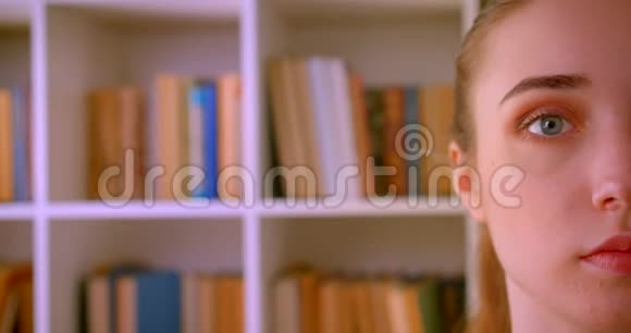 在室内图书馆里看相机的年轻漂亮女学生的特写半脸肖像视频的预览图
