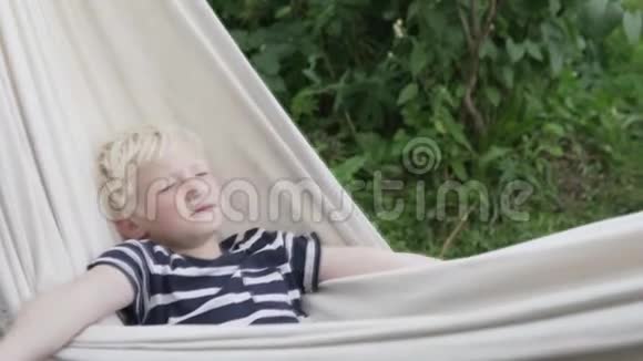 快乐男孩金发女孩夏天睡在小屋的吊床上视频的预览图
