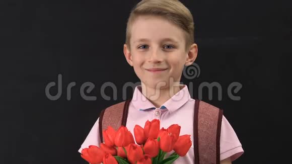 可爱的小男孩带着背包捧着郁金香花束母亲节快乐礼物视频的预览图