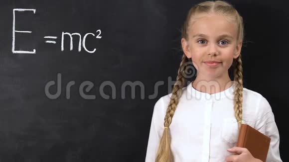 聪明的女学生把粉笔指向黑板上写的物理公式视频的预览图