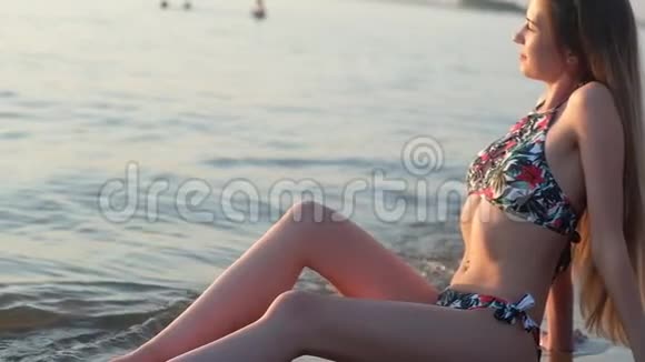 穿着泳衣的年轻迷人的女孩赤着脚跌入海浪中视频的预览图