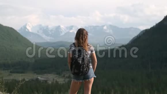穿着短裤背包的女旅行者站在山顶举起双手实现目标视频的预览图