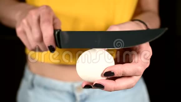 女人拿着刀和白蛋打碎脆弱的蛋黄特写镜头视频的预览图
