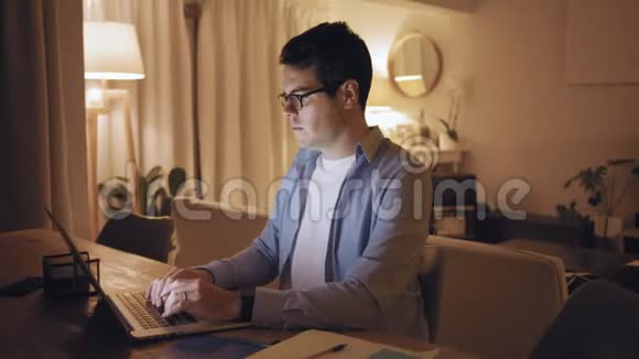 累得脖子疼的男人在笔记本电脑上工作到深夜视频的预览图