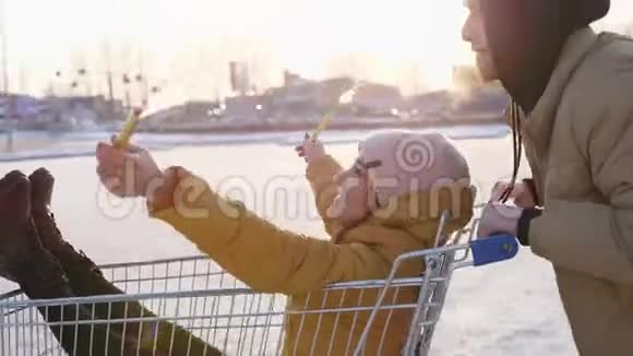 快乐的年轻夫妇骑着手推车在商场停车场阳光照在背景上慢动作视频的预览图
