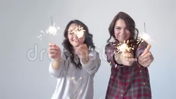 两个穿着睡衣的漂亮女人带着火花庆祝圣诞节慢动作视频的预览图
