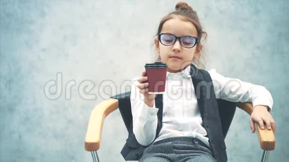 小商人坐在灰色背景的椅子上在这段时间里他喝咖啡商务视频的预览图