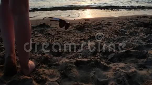 瘦漂亮的女孩把太阳镜扔到潮湿的沙子上跑进大海视频的预览图