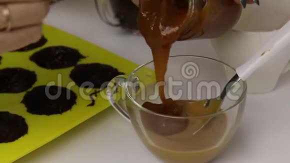 女人把馅料混合成釉面糖果附近是用液体巧克力润滑的硅胶模具视频的预览图